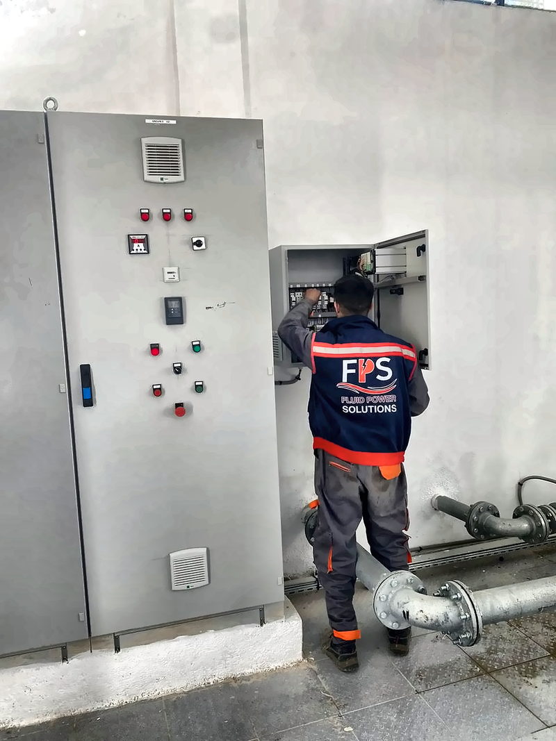 Technicien FPS mettant en service un coffret de commande en station de pompage